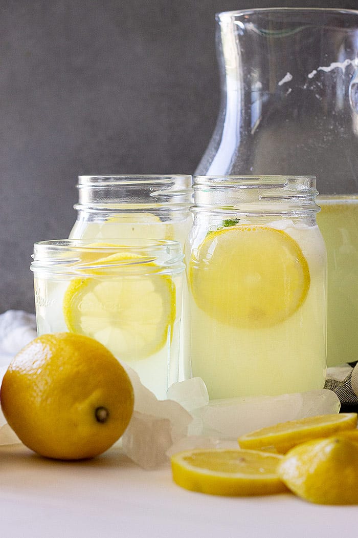 Glasses of lemonade with lemons as garnish.