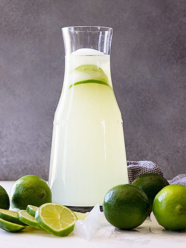 A tall pitcher of limeade with fresh limes as garnish.