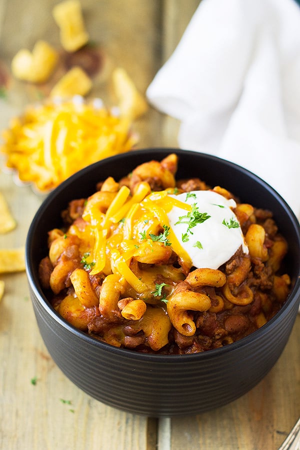 Bowl of chili mac topped with cheese and sour cream.