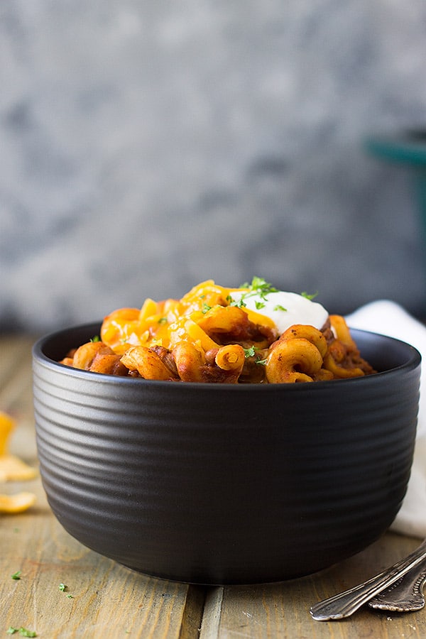 Bowl of chili mac topped with sour cream and cheddar. 
