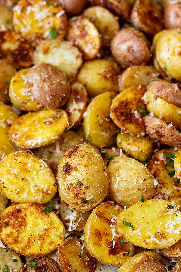 Close up of golden roasted potatoes sprinkled with fresh Parmesan and parsley.