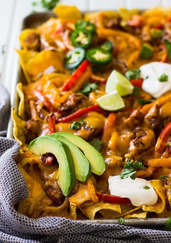 This Sheet Pan Chicken Fajita Nachos is a great game day appetizer for a crowd! Filled with seasoned chicken and vegetables and lots of cheese! | www.countrysidecravings.com