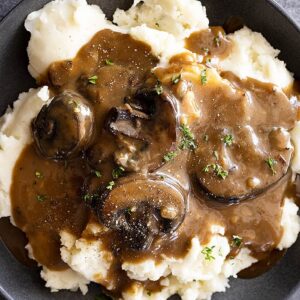 Overhead view of mushroom gravy over mashed potatoes and garnished with pepper and parsley.