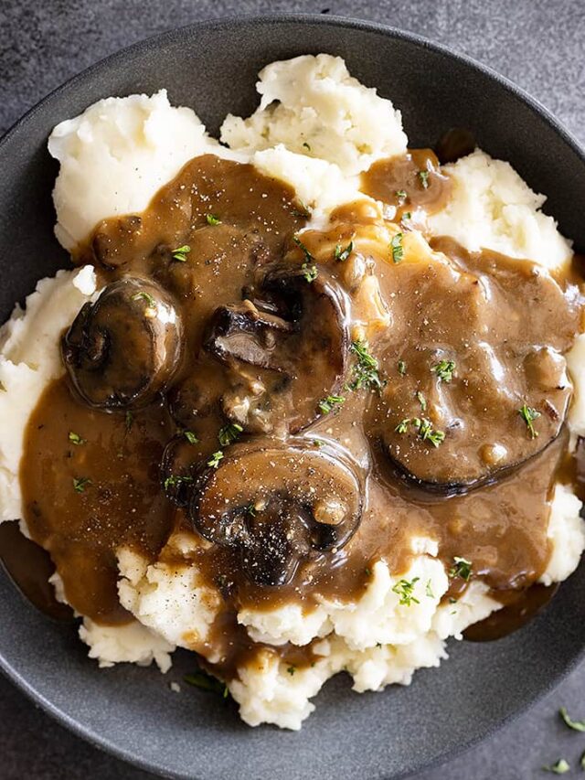 Overhead view of mushroom gravy over mashed potatoes and garnished with pepper and parsley.