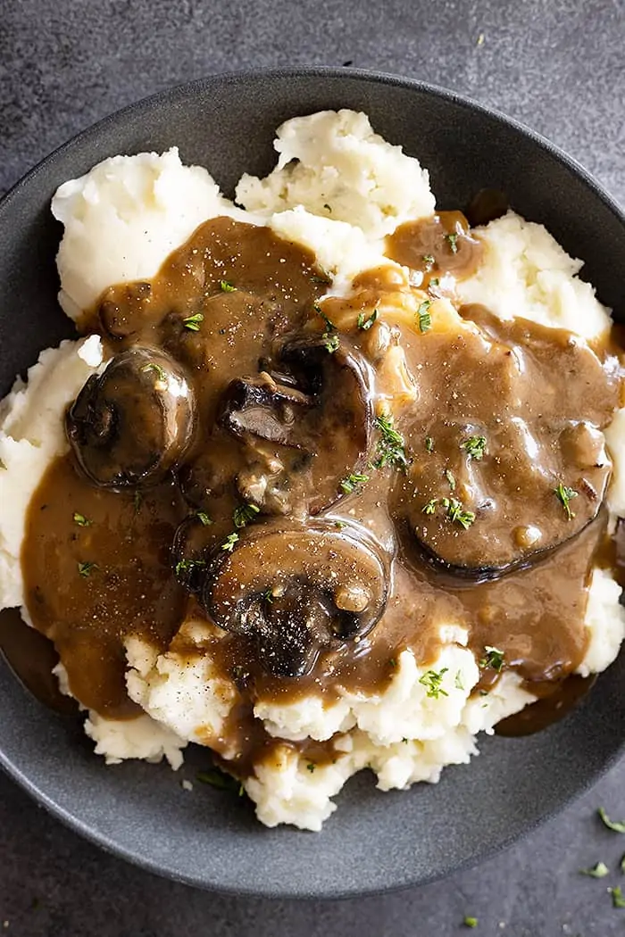 Overhead view of mushroom gravy over mashed potatoes and garnished with pepper and parsley.