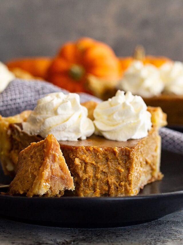 Close up of a slice of traditional pumpkin pie with a bite taken out to show how smooth and creamy it is.