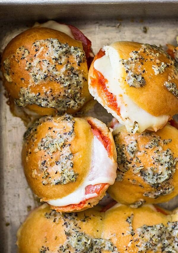 Overhead view of sliders in a pan. Can see the melty cheese and yummy topping.