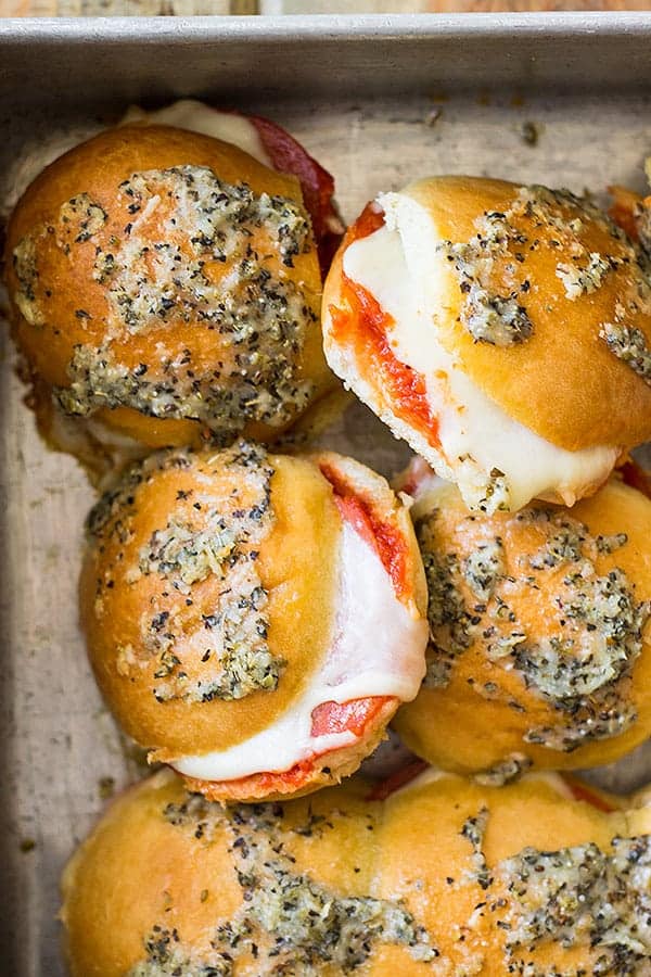Overhead view of sliders in a pan. Can see the melty cheese and yummy topping.