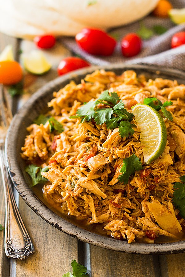 crockpot mexican chicken in a bowl with lime wedges