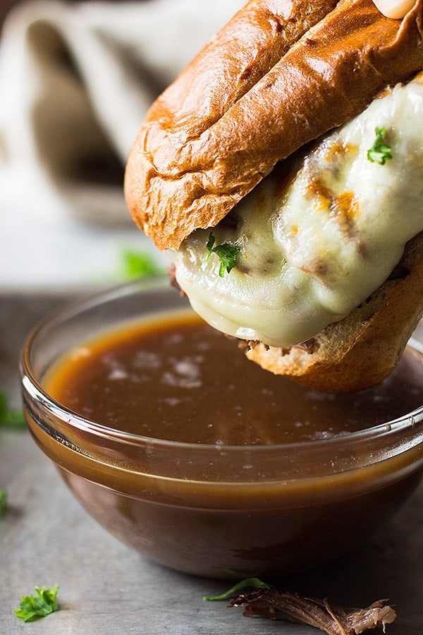 A french dip sandwich dipping into au jus. 
