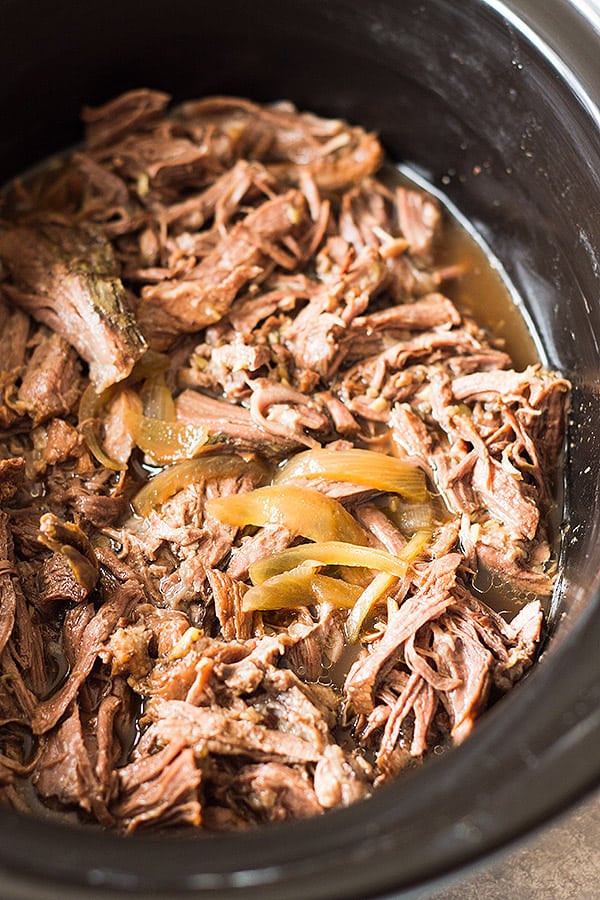 Shredded beef and sliced onions in a crockpot. 