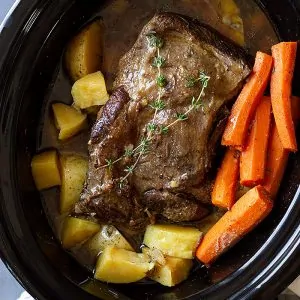 pot roast in slow cooker with carrots and potatoes.