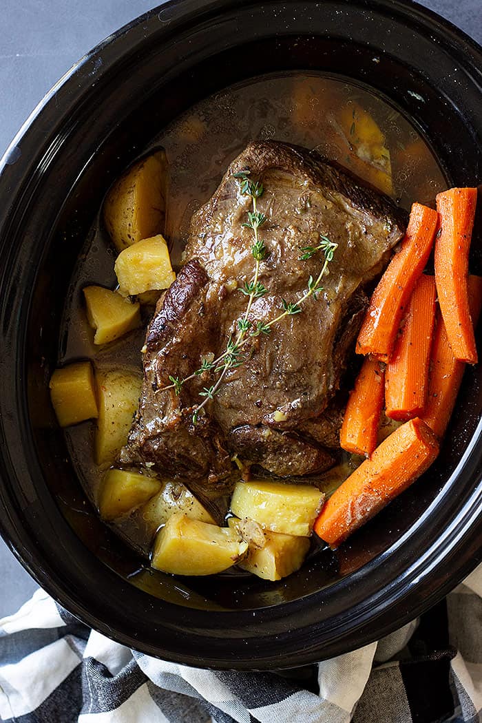 pot roast in slow cooker with carrots and potatoes.