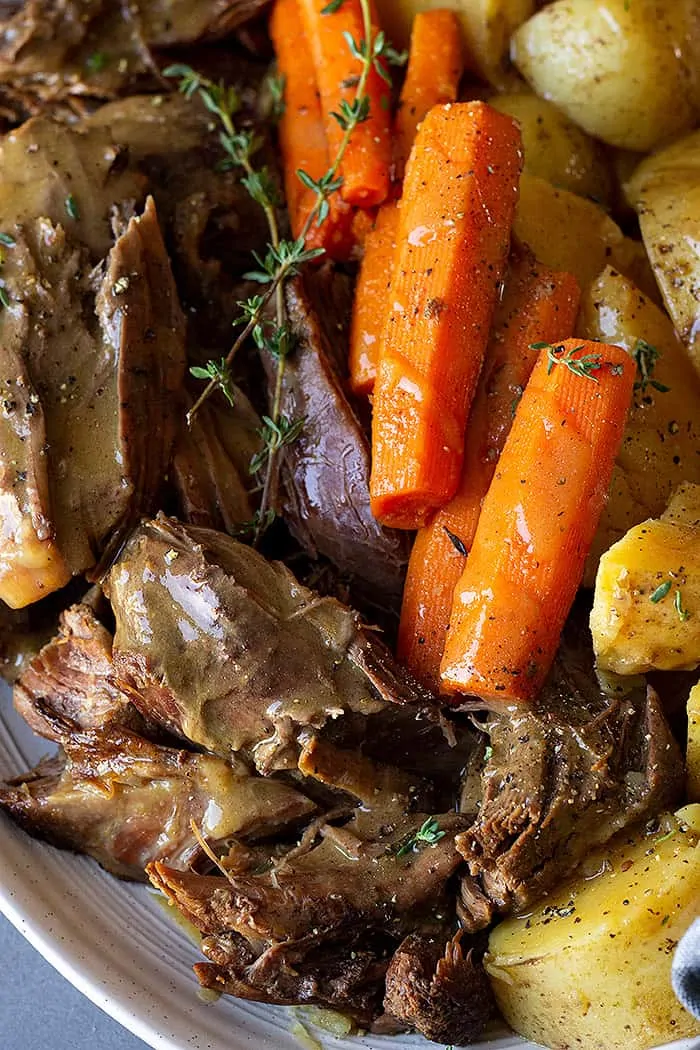 Close up of roast on a serving plate with gravy. 