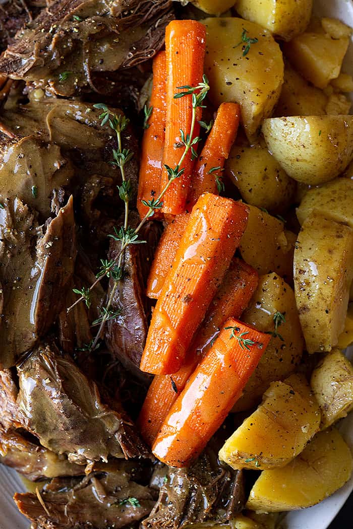 Close up of roast and veggies garnished with thyme. 
