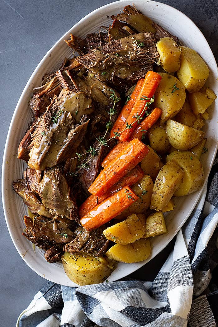 Top down view of roast, carrots, and potatoes on a serving plate. 