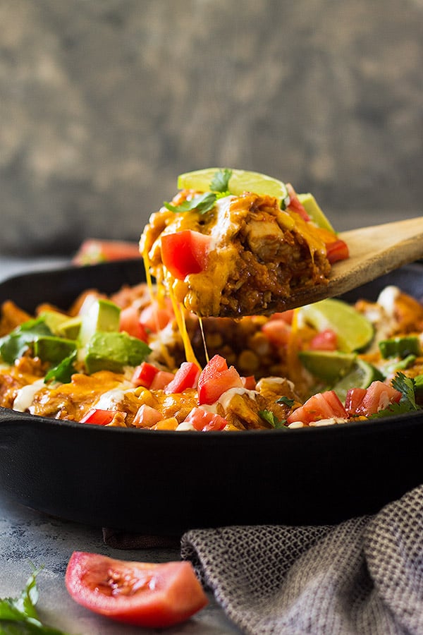 side view closeup: a wooden spoon lifting a big spoonful of barbeque chicken and rice out of the skillet