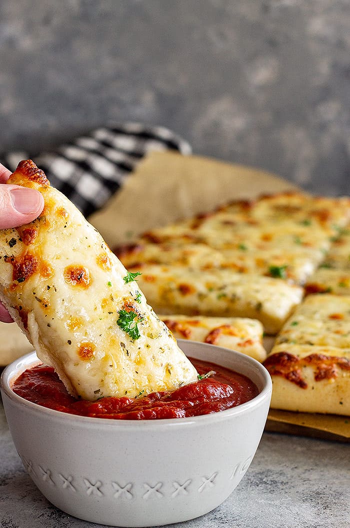 Bread stick being dunked into sauce.