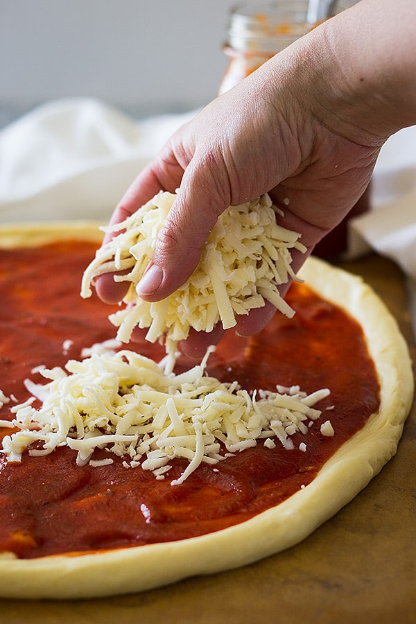 Sprinkling pizza with cheese. 
