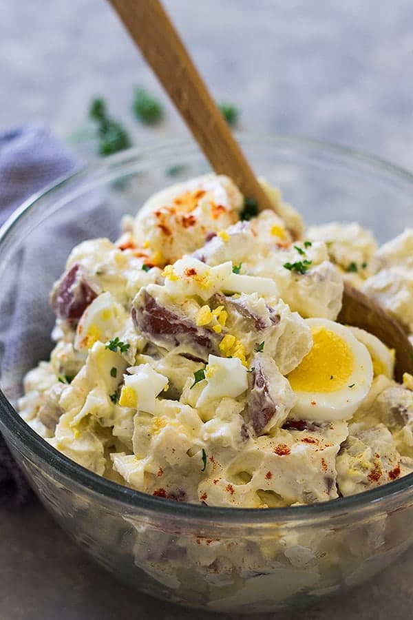 Front view of potato salad with wooden spoon.