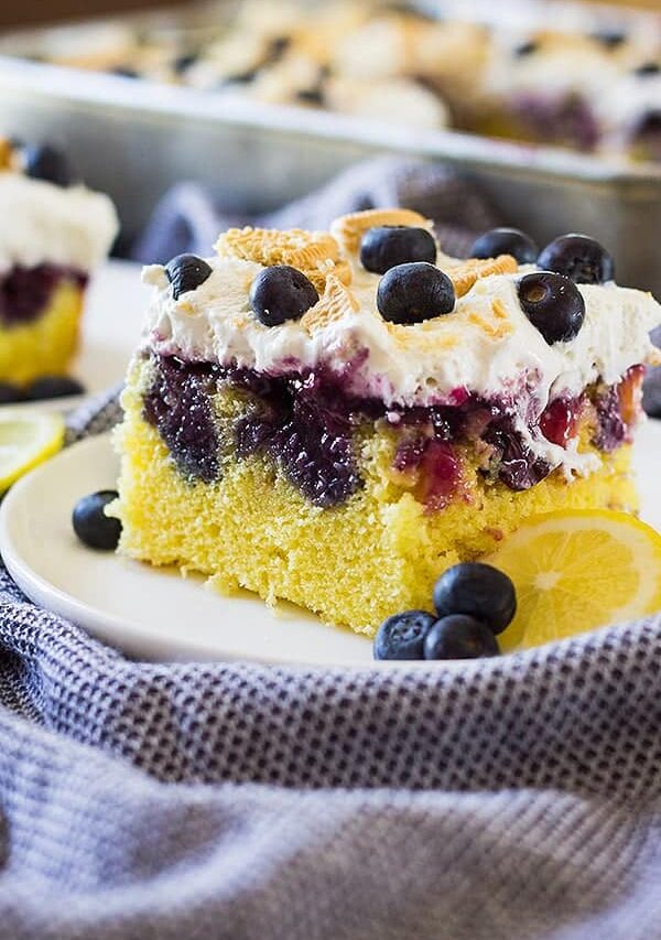 One piece of lemon blueberry poke cake on white plate with blueberries