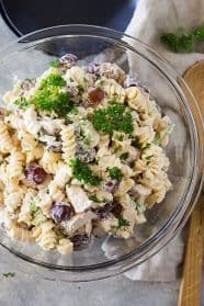 top shot of pasta salad with red grapes in clear glass mixing bowl