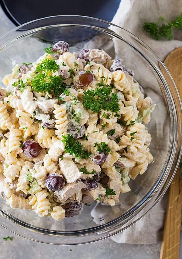 top shot of pasta salad with red grapes in clear glass mixing bowl