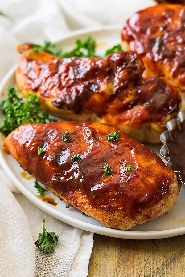 Chicken breasts with sauce on top on white plate.