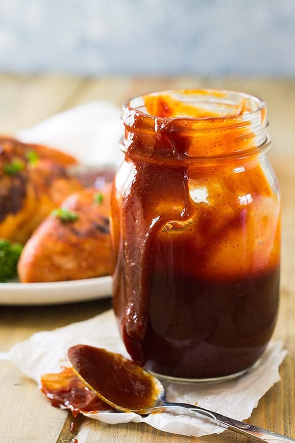 Closeup shot of Kansas City Style BBQ Sauce in mason jar with spoon next to it.