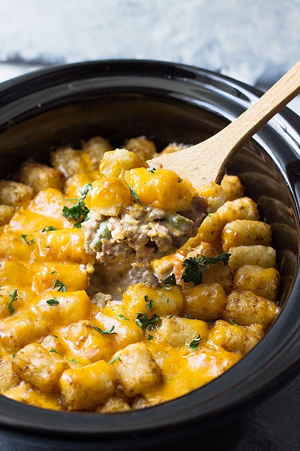 Spoonful of Bacon Cheeseburger Tater Tot Casserole coming out of slow cooker. 