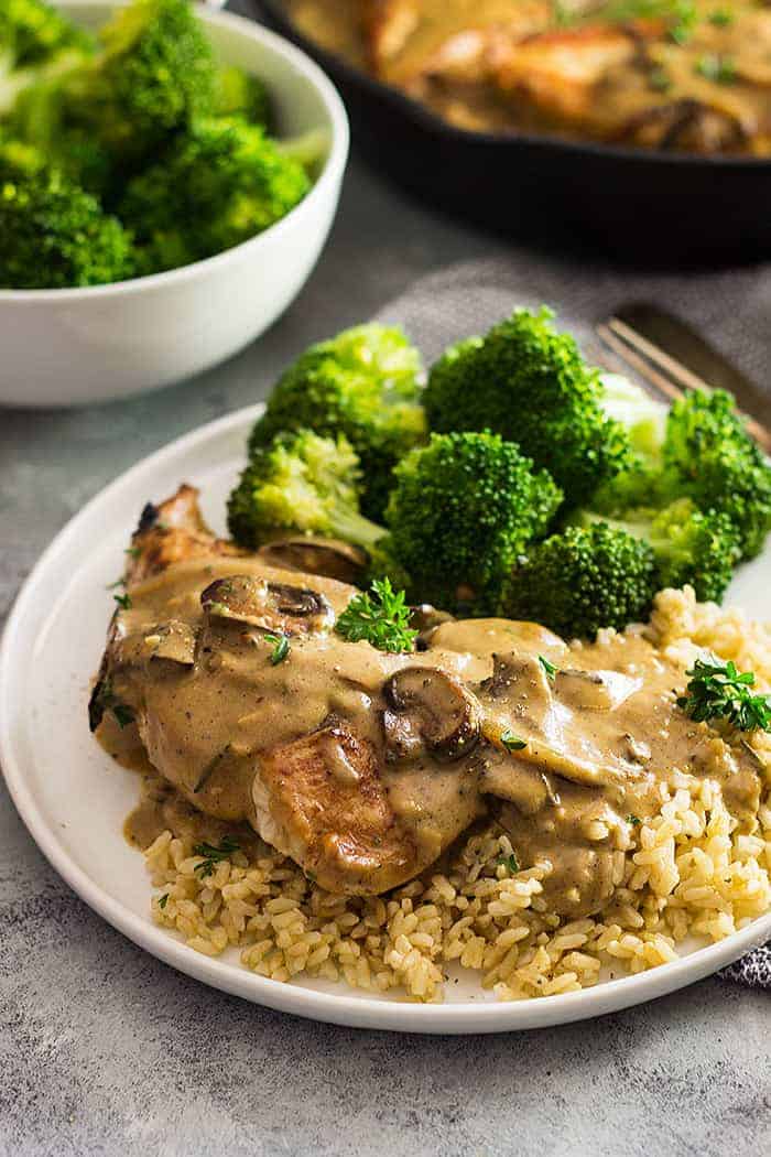 White plate with broccoli, rice, chicken, and a mushroom cream sauce drizzled on top