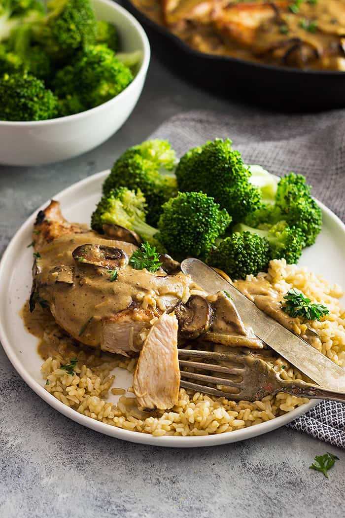 White plate with broccoli, rice, chicken, and a mushroom cream sauce drizzled on top