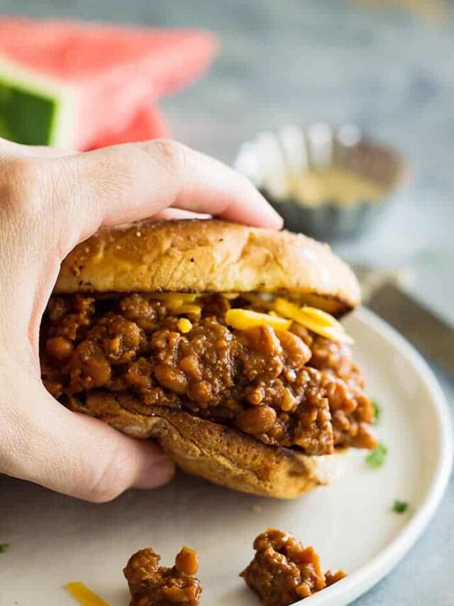 hand holding slow cooker beef and bean sloppy joes above white plate