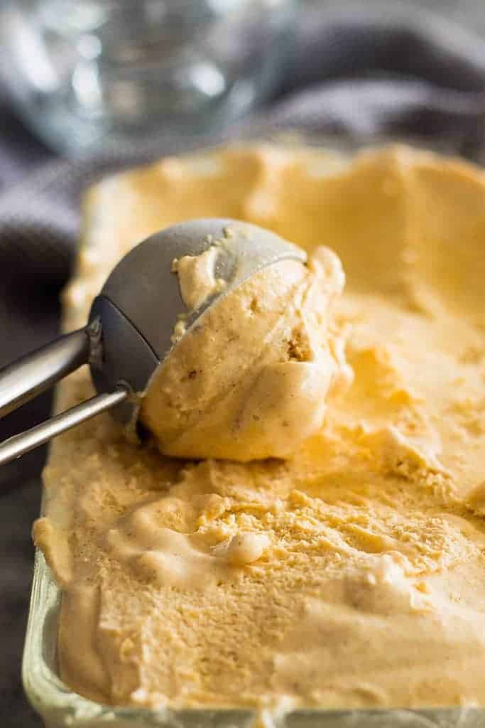 scooping no churn pumpkin ice cream out of a container