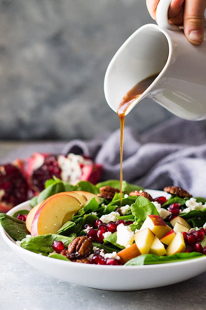 drizzling dressing on spinach apple salad