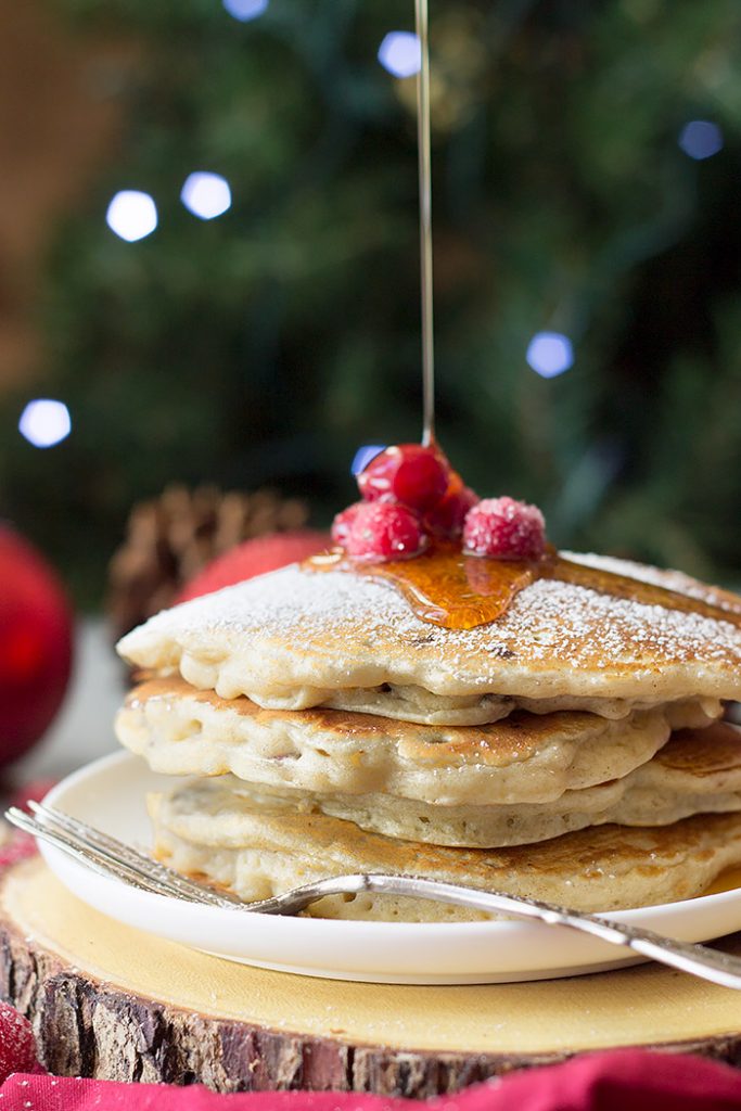 A stack of cranberry chocolate chip pancakes being drizzled with maple syrup. 