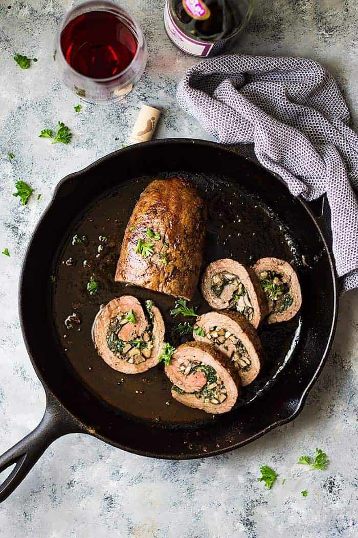 Cast iron skillet with partially sliced Mushroom and Blue Cheese stuffed flank steak. 