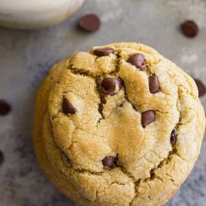 A top down view of a chocolate chip cookie and a glass of milk.