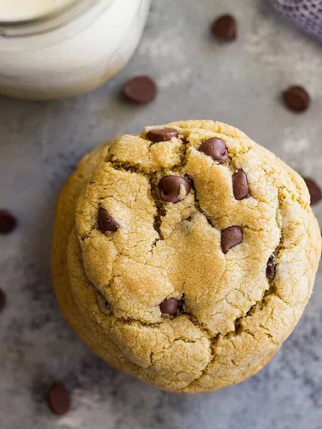 A top down view of a chocolate chip cookie and a glass of milk.