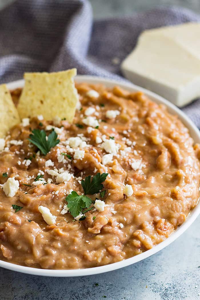 Big bowl of refried beans topped with cheese and a couple of chips dipped in. 