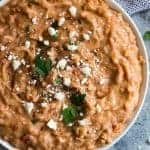 Overhead shot of a bowl of refried beans sprinkled with cheese.