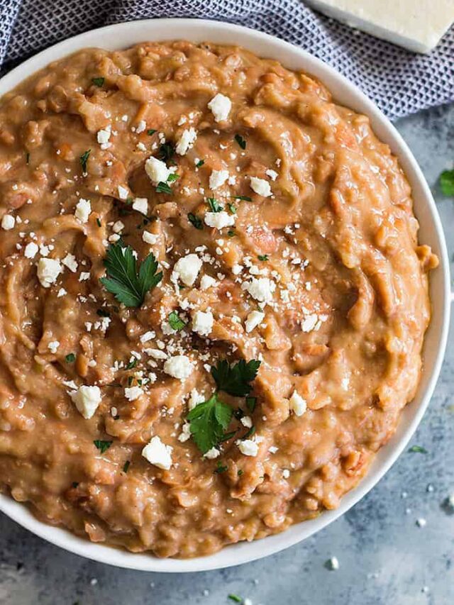 Overhead shot of a bowl of refried beans sprinkled with cheese.