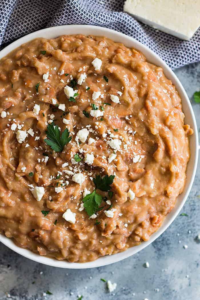 Overhead shot of a bowl of refried beans sprinkled with cheese. 