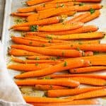 Honey garlic roasted carrots on a sheet pan garnished with parsley.