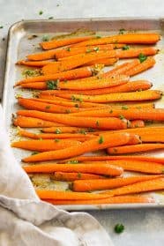 Honey garlic roasted carrots on a sheet pan garnished with parsley.