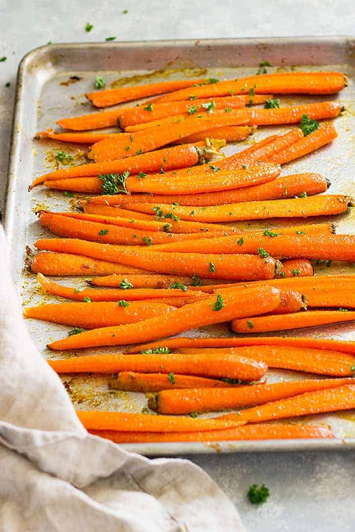 Honey garlic roasted carrots on a sheet pan garnished with parsley. 