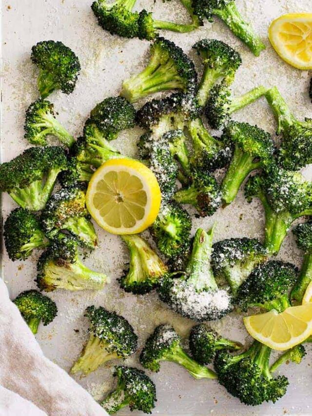 Top down view of lemon parmesan roasted broccoli on a sheet pan with lemon slices.