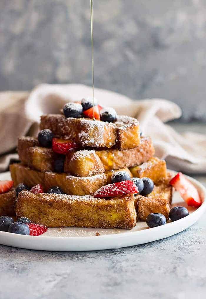 drizzling stack of french toast sticks with syrup