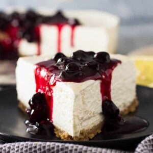 Close up of a slice of No Bake Lemon Blueberry Cheesecake with blueberry sauce on top.