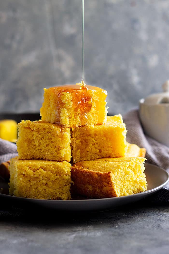 plate with cornbread with buttermilk being drizzled in honey